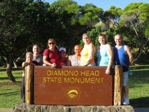 Group of people standing behind Diamond Head State Monument sign